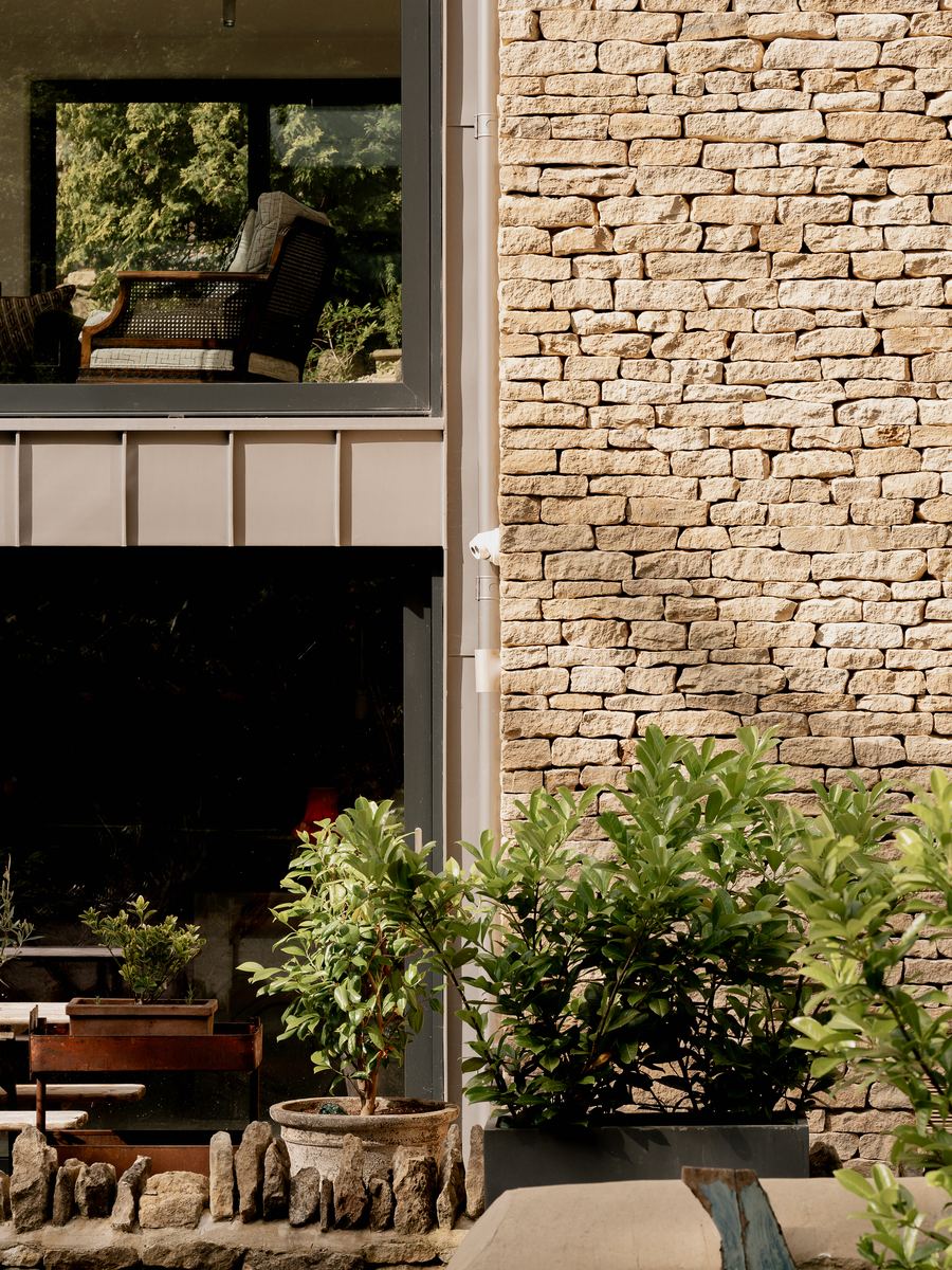 Cotswold Cottage Extension detail of dry-stone walling beside large-format glazing and standing-seam zinc cladding